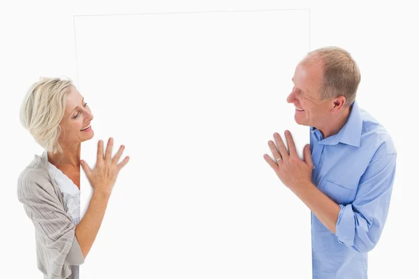 Pareja madura sonriendo y sosteniendo la tarjeta — Foto de Stock