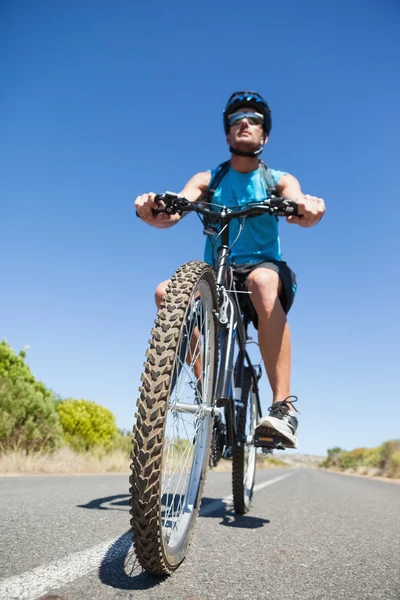 Athletic man cycling on open road — Stock Photo, Image