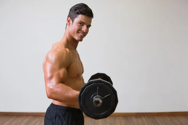 Shirtless muscular man lifting barbell in gym — Stock Photo, Image