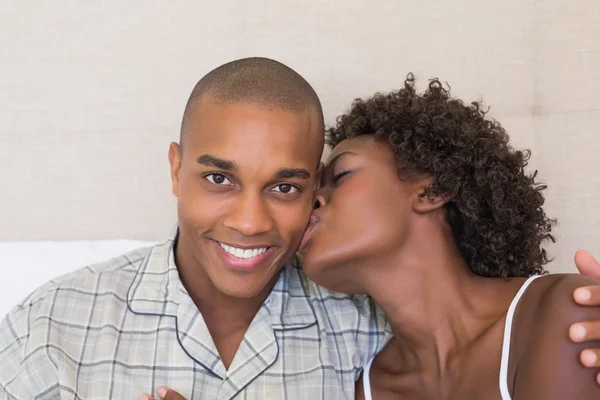 Happy couple sitting on bed cuddling — Stock Photo, Image