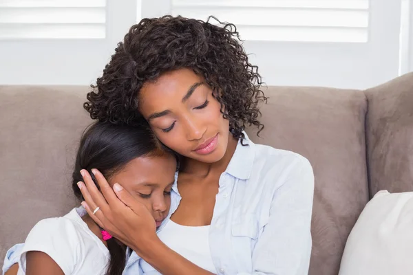 Pretty mother sitting on the couch with her sleeping daughter — Stock Photo, Image