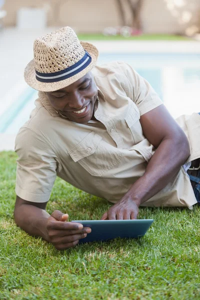 Smiling man relaxing in his garden using tablet pc — Stock Photo, Image