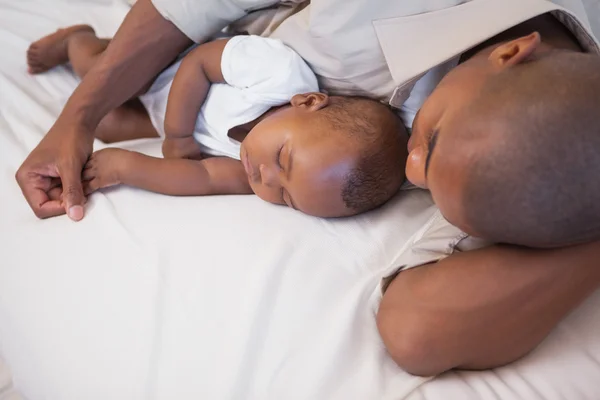 Father napping with baby son on couch Royalty Free Stock Images