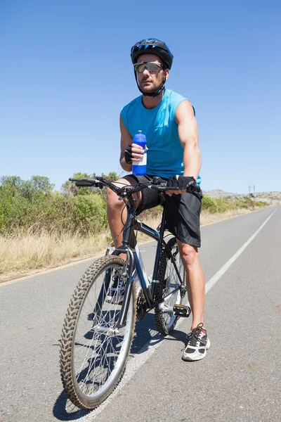 英俊骑自行车的人，在他的自行车上休息 免版税图库图片