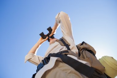 Hiker looking through binoculars on country trail clipart