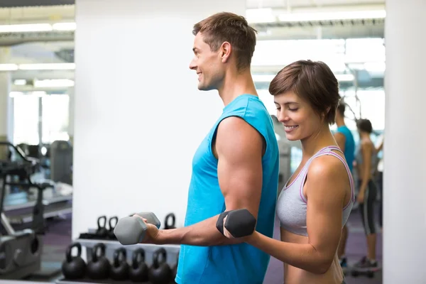 Fit happy couple lifting dumbbells together — Stock Photo, Image