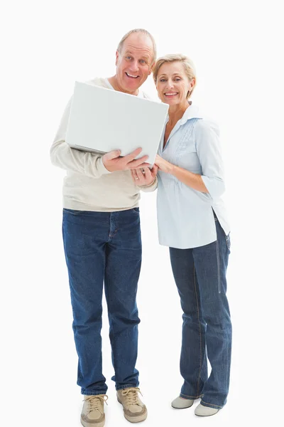 Coppia matura sorridente alla fotocamera con computer portatile — Foto Stock