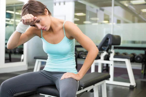 Fit brunette sitting on bench wiping forward — Stock Photo, Image