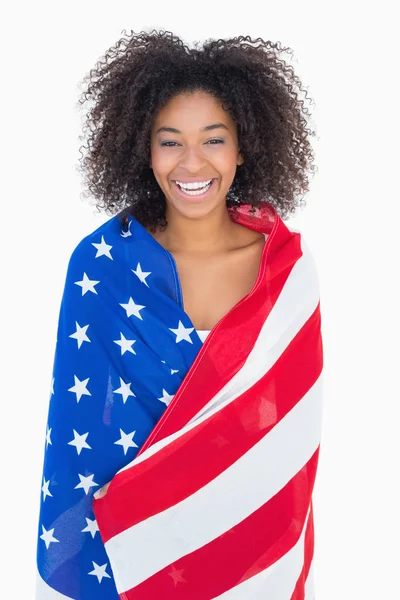 Linda chica envuelta en bandera americana sonriendo a la cámara — Foto de Stock