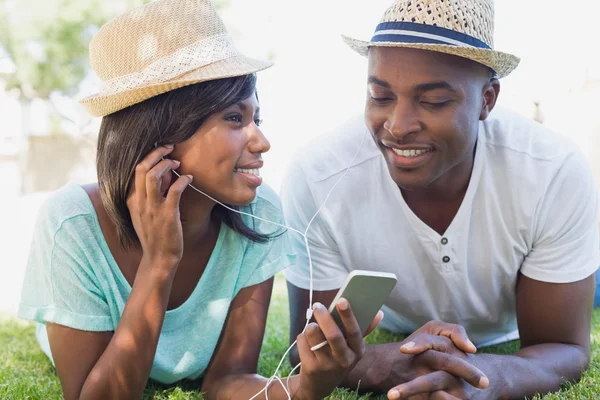 Pareja feliz tumbada en el jardín escuchando música —  Fotos de Stock