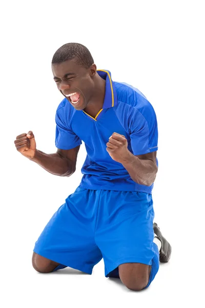 Emocionado jugador de fútbol en azul animando en sus rodillas —  Fotos de Stock