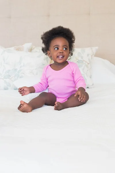 Petite fille en rose Mamagoose assis sur le lit — Stock fotografie