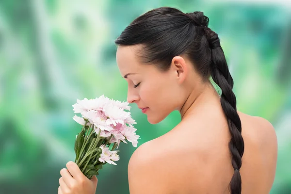 Beautiful nude brunette smelling bunch of pink flowers — Stock Photo, Image