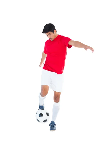 Fotbollsspelare i rött sparkar boll — Stockfoto