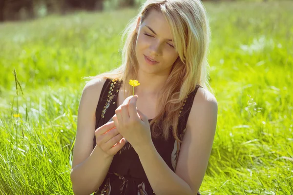 Loira bonita em sundress segurando flor amarela — Fotografia de Stock