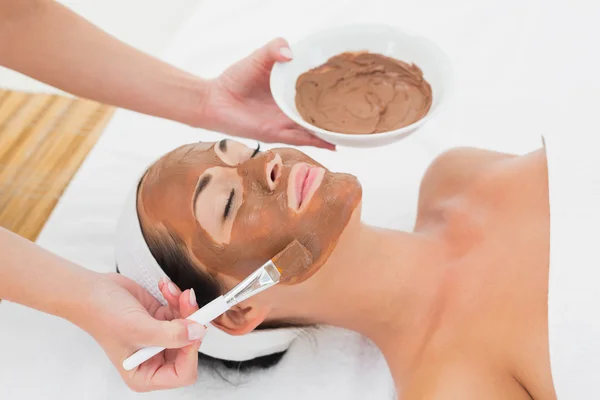 Smiling brunette getting a mud treatment facial — Stock Photo, Image