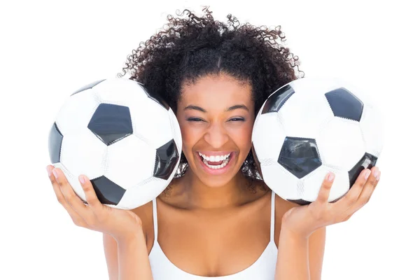 Красивая девушка держит футбольные мячи и смеется над камерой — стоковое фото