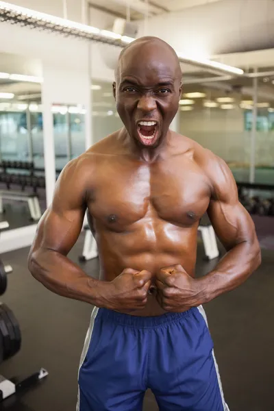 Uomo muscolare urla mentre flette i muscoli in palestra — Foto Stock