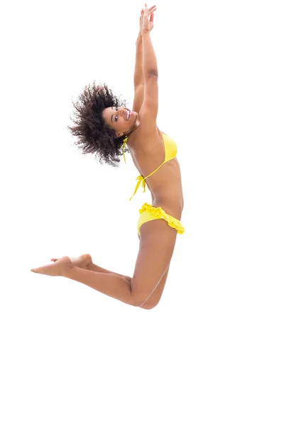 Fittes Mädchen im gelben Bikini hüpft und lächelt in die Kamera — Stockfoto