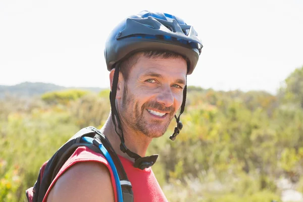 Fit cyclist smiling at the camera on country terrain — Stock Photo, Image