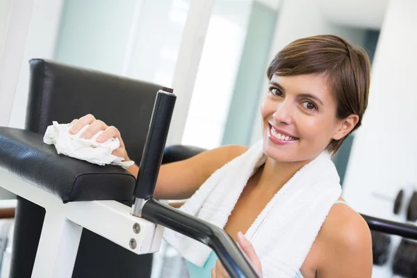 Ajuste morena limpiando banco sonriendo a la cámara — Foto de Stock