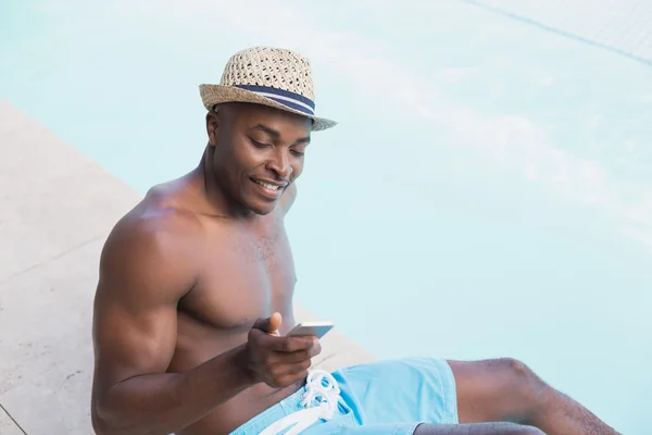 Handsome shirtless man texting on phone poolside — Stock Photo, Image