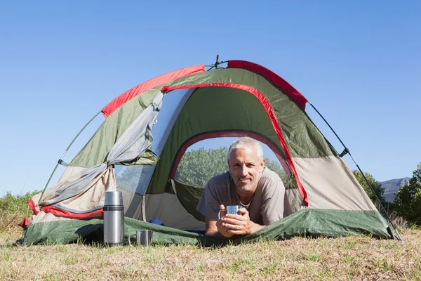 Glücklicher Camper lächelt in die Kamera, die in seinem Zelt liegt — Stockfoto