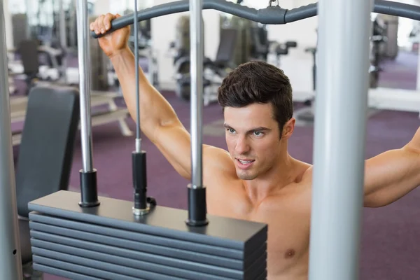 Hombre musculoso haciendo ejercicio en una máquina lat en el gimnasio —  Fotos de Stock