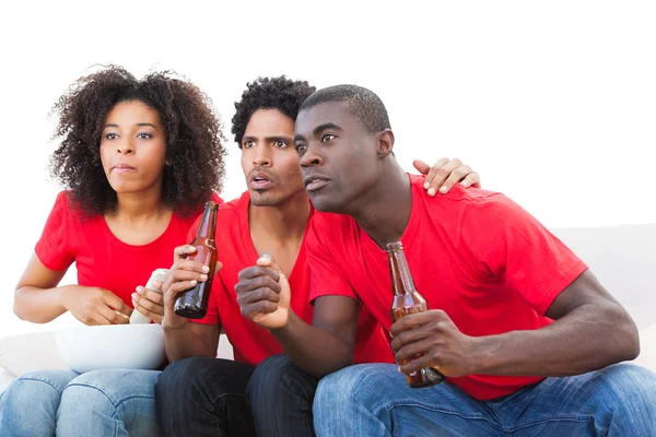 Nervous football fans in red on the sofa — Stock Photo, Image