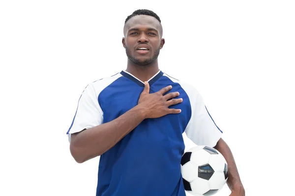 Jogador de futebol em pé azul com a bola ouvindo anth — Fotografia de Stock