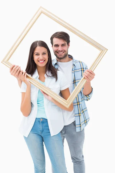 Happy young couple holding picture frame — Stock Photo, Image