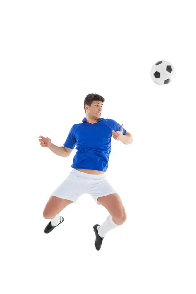 Joueur de football en maillot bleu sautant au ballon — Photo