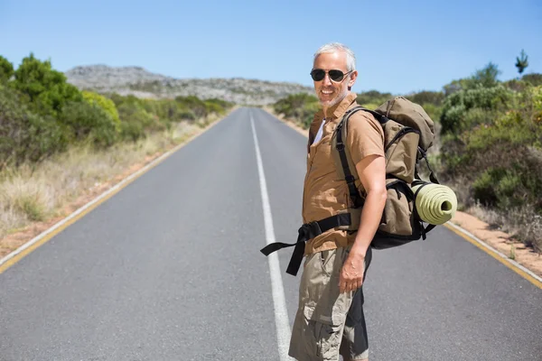 Stilig vandrare vandring på vägen och ler mot kameran — Stockfoto