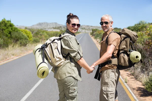 Hitch caminhadas casal de pé de mãos dadas na estrada — Fotografia de Stock