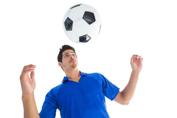 Jogador de futebol em azul saltando para a bola — Fotografia de Stock
