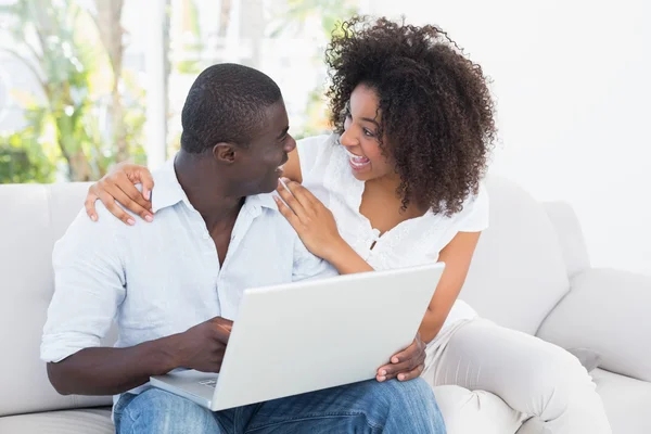 Atractiva pareja usando el ordenador portátil juntos en el sofá — Foto de Stock