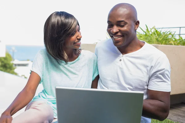 Lyckliga paret sitter i trädgården med laptop tillsammans — Stockfoto