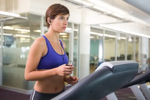 Fit brunette running on the treadmill listening to music — Stock Photo, Image