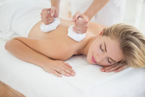 Schöne Blondine genießt eine Kräuterkompresse Massage — Stockfoto