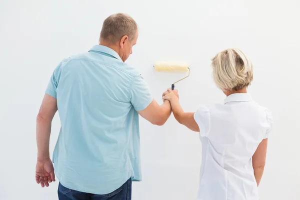 Feliz casal mais velho pintura parede branca — Fotografia de Stock