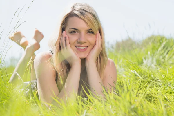 Bonita rubia en vestido de sol acostada en la hierba sonriendo a la cámara —  Fotos de Stock