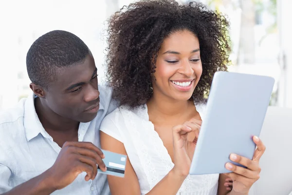 Atractiva pareja usando la tableta juntos en el sofá para comprar en línea —  Fotos de Stock