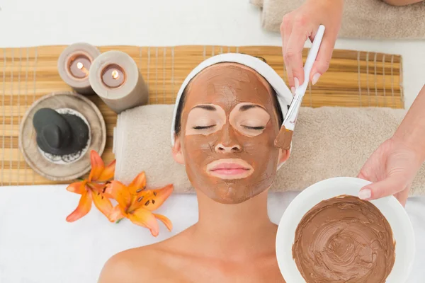 Peaceful brunette getting a mud treatment facial — Stock Photo, Image