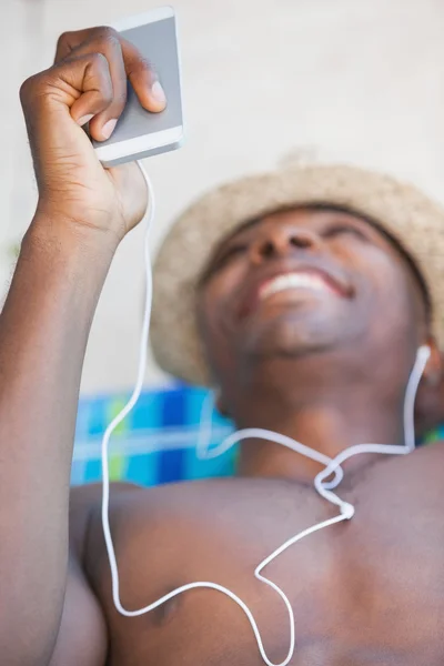 Hombre sin camisa sonriendo y escuchando música en el teléfono inteligente —  Fotos de Stock
