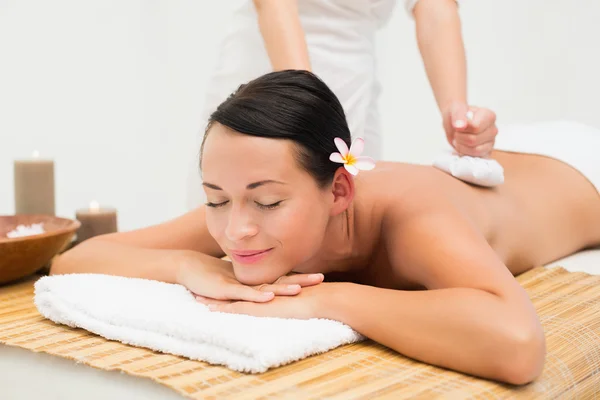 Peaceful brunette enjoying a herbal compress massage — Stock Photo, Image