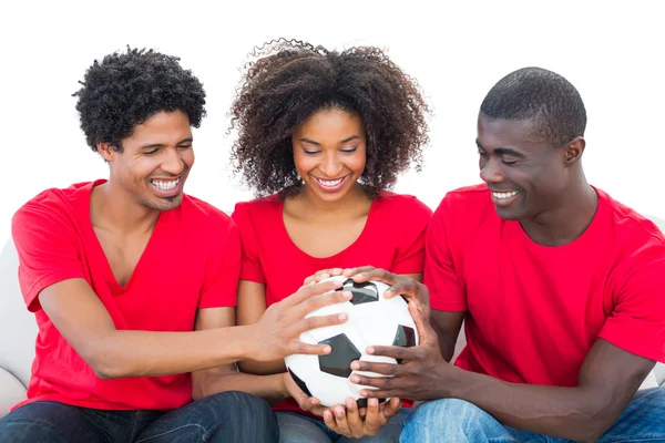 Fãs de futebol em vermelho segurando bola juntos — Fotografia de Stock