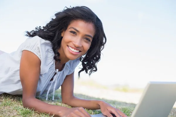Frau liegt mit Laptop im Gras — Stockfoto