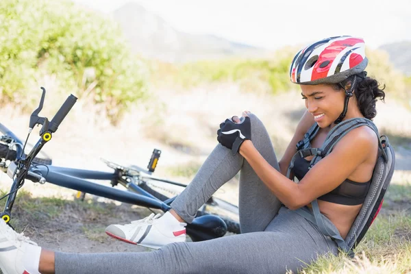 Fit woman holding her injured knee after bike crash — Stock Photo, Image