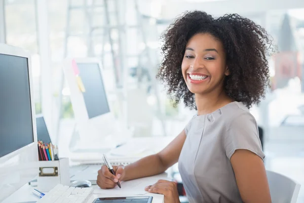 Young pretty designer smiling at camera at her desk — Stock Photo, Image