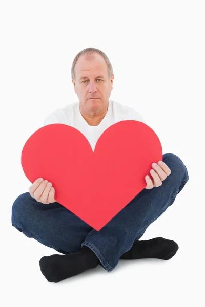 Αναστατωμένος άνθρωπος κάθεται κρατώντας το σχήμα καρδιάς — Φωτογραφία Αρχείου